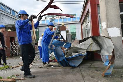 Trabajadores retiran escombros el sábado 15 de mayo de 2021 de una fábrica dañada por un tornado en la localidad de Shengze, en la provincia oriental de Jiangsu, China. (Chinatopix vía AP)