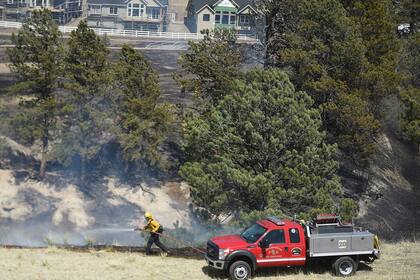Un bombero combate las llamas el viernes 22 de abril de 2022, en Colorado Springs, Colorado. (Jerilee Bennett/The Gazette vía AP)