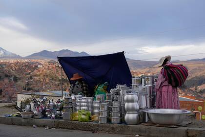 Un cliente mira los productos de un vendedor de ollas de aluminio durante una tradicional feria semanal en El Alto, Bolivia, el jueves 24 de noviembre de 2022. La Comisión Económica para América Latina y el Caribe (CEPAL) estima que la región crecerá un 3,7% en 2022, casi la mitad del 6,7% registrado en 2021; y sólo un 1,3% el año próximo (AP Foto/Juan Karita)