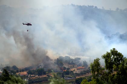 Un helicóptero vuela sobre el poblado de Markati, a unos 60 kilómetros (37 millas) al sur de Atenas, Grecia, el lunes 16 de agosto de 2021. (AP Foto/Thanassis Stavrakis)