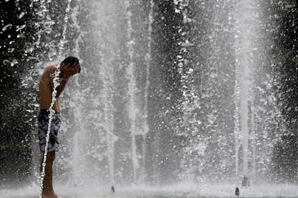 Un hombre se refresca junto a una fuente de agua durante una ola de calor en Sevilla el 10 de julio de 2023. Las temperaturas subieron en toda España el 10 de julio con el mercurio a punto de tocar los 44 grados Celsius en el sur mientras el país se preparaba para su segunda ola de calor en quince días
