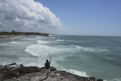 Un hombre toma un video desde la costa rocosa de la playa Mirador antes de la llegada prevista del huracán Beryl, en Tulum, México