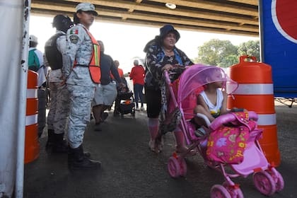 Un migrante empuja un cochecito de bebé frente a la Guardia Nacional en Tapachula, en el estado mexicano de Chiapas. (Archivo AP Foto/Edgar H. Clemente)