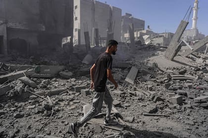 Un palestino camina entre los escombros de edificios tras una operación de las fuerzas especiales israelíes en Nuseirat