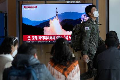 Un soldado del ejército de Corea el Sur camina junto a una pantalla de televisión que muestra una imagen de archivo de un lanzamiento de misil norcoreano en un programa noticioso, el miércoles 2 de noviembre de 2022, en la Estación de Tren de Seúl. (AP Foto/Ahn Young-joon)