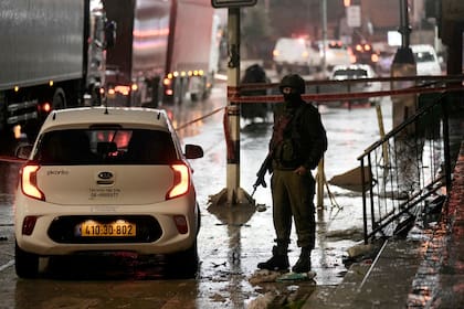 Un soldado israelí trabaja en la escena donde un palestino abrió fuego contra un vehículo israelí, hiriendo a dos personas, en Hawara, Cisjordania, el 19 de marzo de 2023. (Foto AP/Majdi Mohammed)