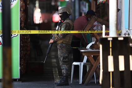 Un soldado vigla el perímetro de un sitio donde se cometió un delito en un pequeño mercado, el domingo 27 de marzo de 2022, en San Salvador, El Salvador. (AP Foto/Salvador Meléndez)