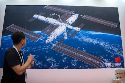 Un visitante observa un mural con una representación de la estación espacial de China en la Conferencia Mundial de Robótica, en Beijing, el 11 de septiembre de 2021. (AP Foto/Mark Schiefelbein)