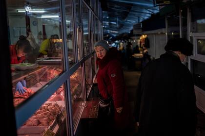 Una mujer compra carne en un mercado en Kiev, Ucrania, el jueves 1 de diciembre de 2022. (AP Foto/Bernat Armangue)