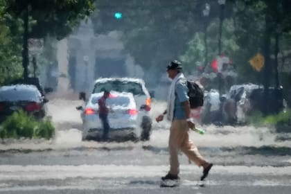 Una persona cruza Caroline Street bajo el calor de la tarde del sábado 25 de mayo de 2024, cerca de Discovery Green, en el centro de Houston. (Jon Shapley/Houston Chronicle via AP)
