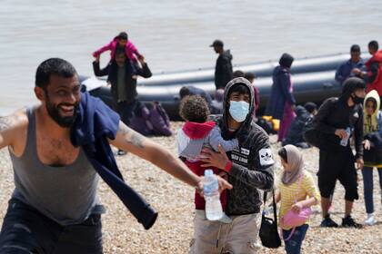 Varias personas en la playa tras desembarcar de un bote en Dungeness, Kent, Inglaterra, el lunes 19 de julio de 2021. Más tarde fueron detenidas por personal de control de fronteras. (Gareth Fuller/PA via AP)