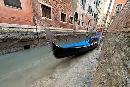 Una góndola está atracada en un canal seco durante la marea baja en Venecia, Italia, el lunes 20 de febrero de 2023