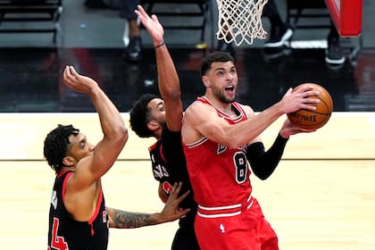 Zach LaVine, de los Bulls de Chicago, avanza hacia la cesta delante de Khem Birch (izquierda) y Jalen Harris, de los Raptors de Toronto, en el encuentro del jueves 13 de mayo de 2021 (AP Foto/Nam Y. Huh)